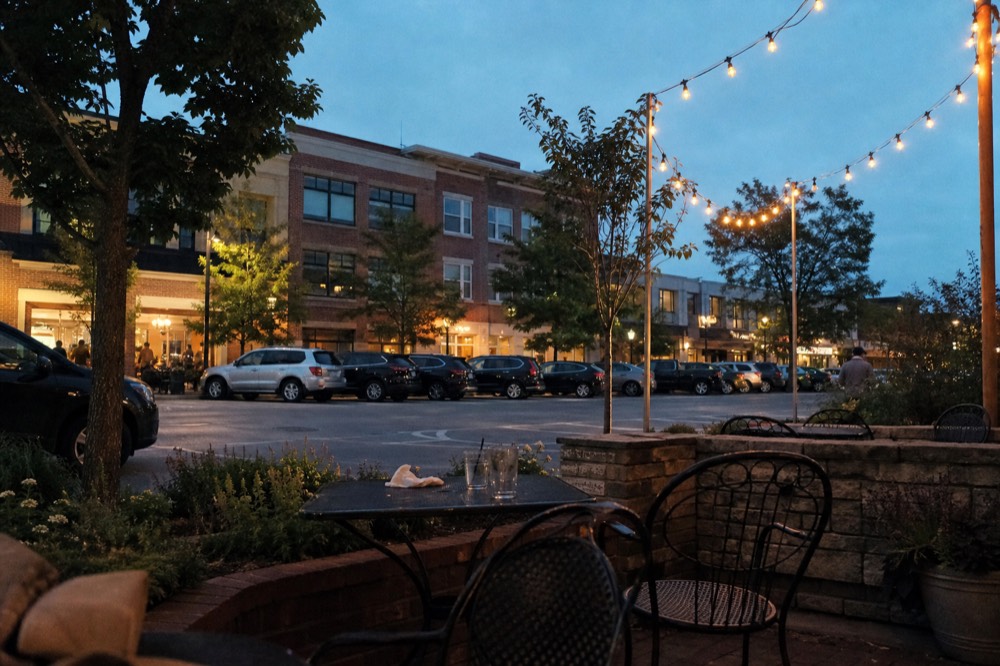 Evening light on a downtown street with restaurant patios and string lights