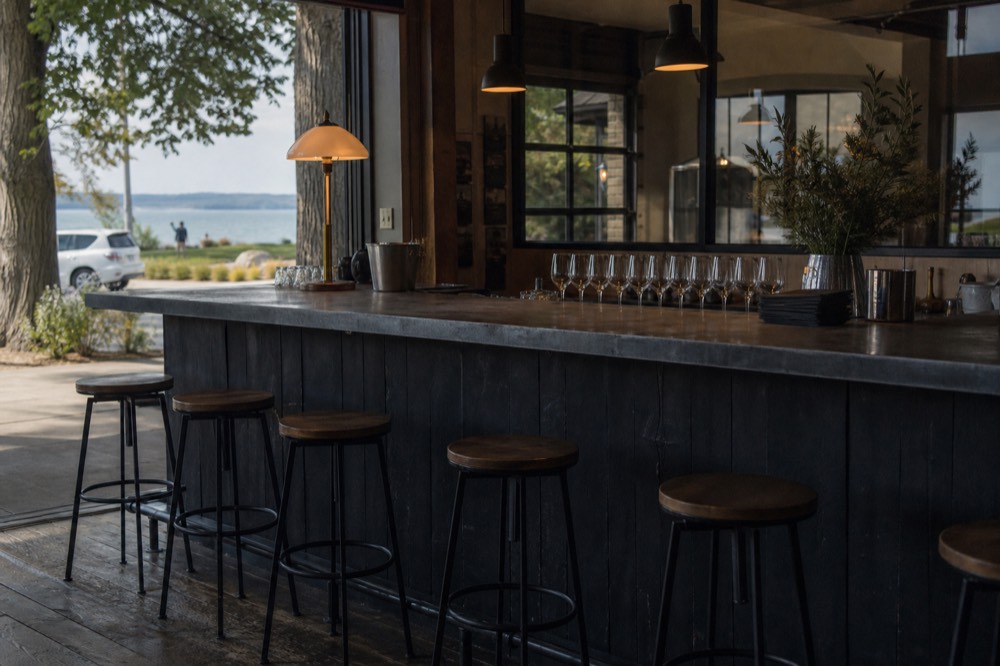 Small tasting room bar with empty stools and wine glasses lined up