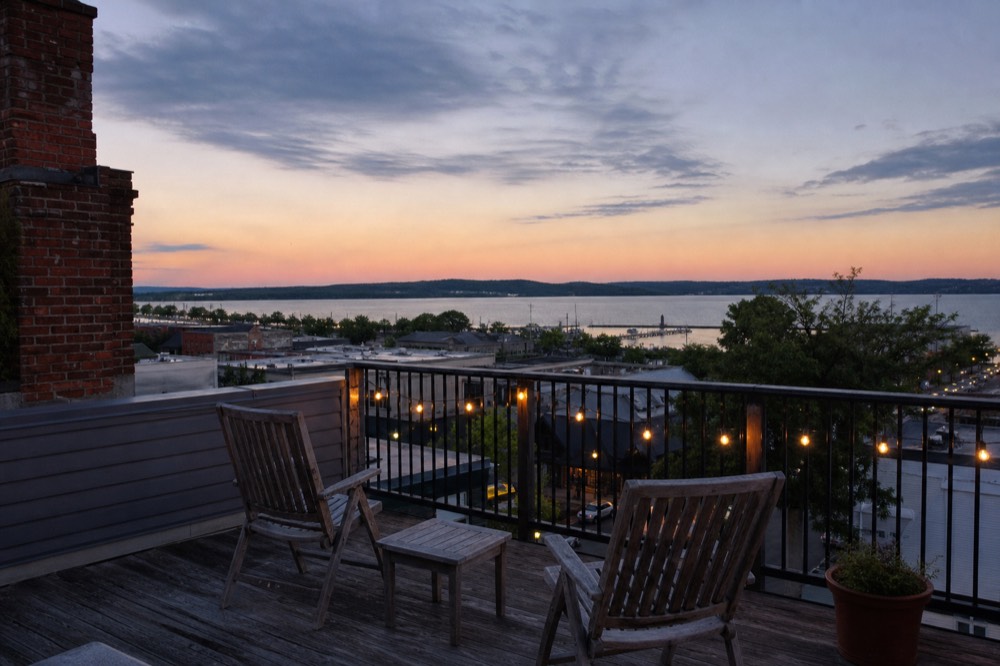 A small inn terrace with two chairs facing water at dusk