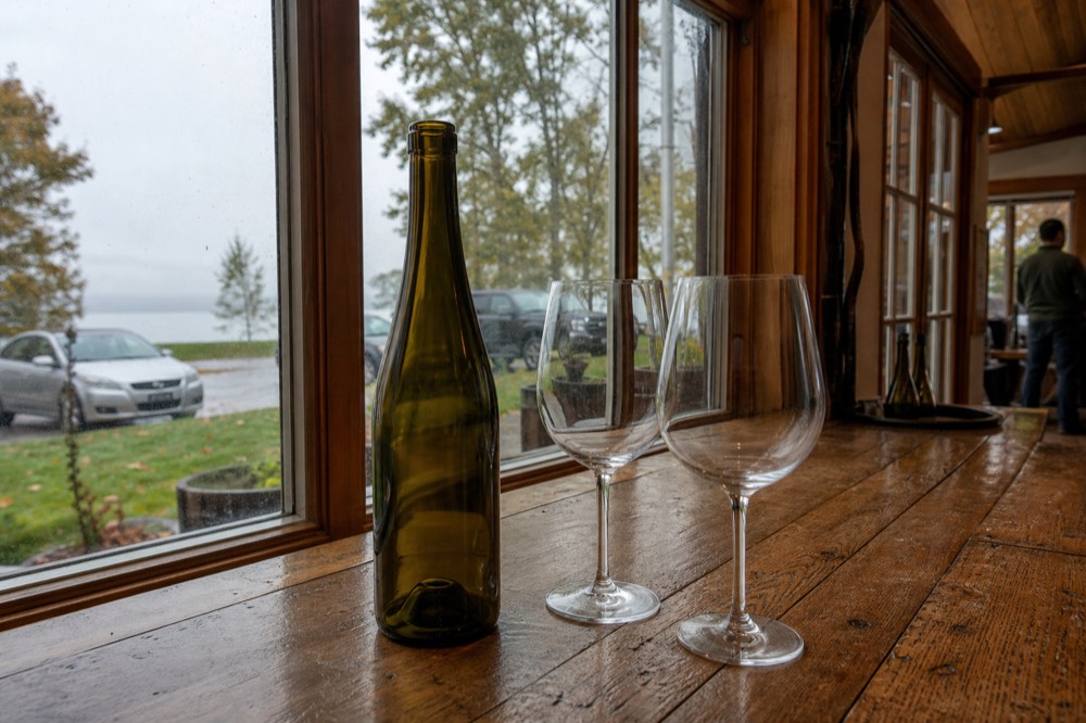 A wine bottle standing on a counter next to two empty stemmed glasses