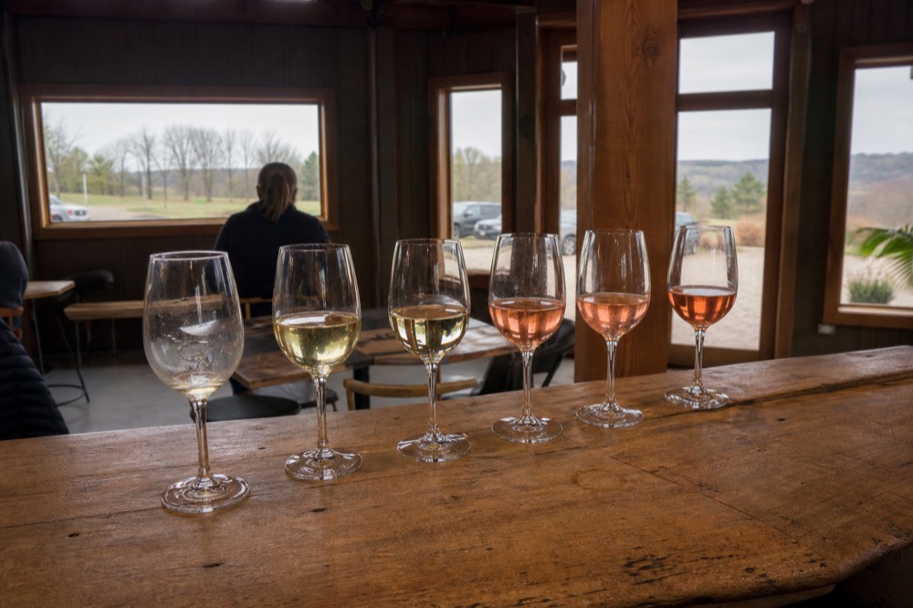 A tasting flight of white and rose wines on a wooden tasting room bar