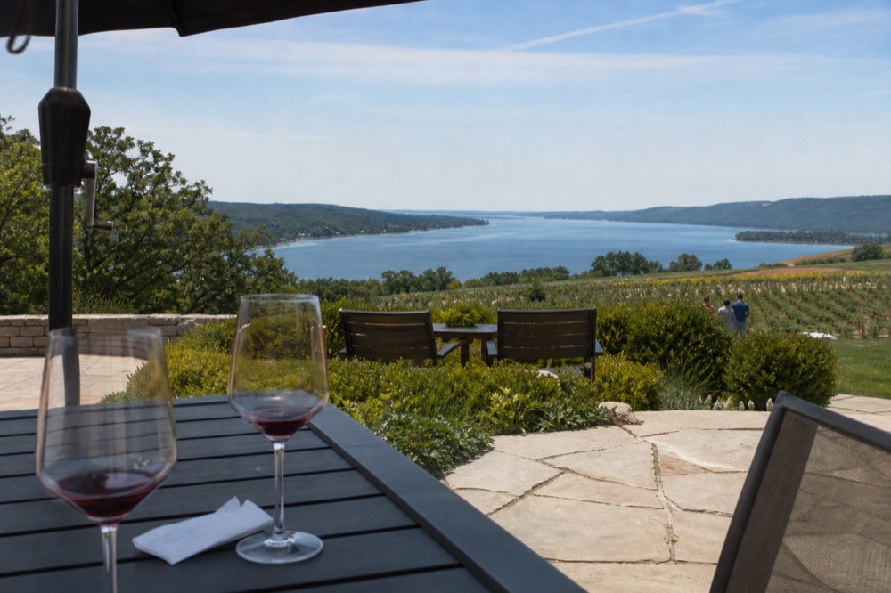 A tasting room patio overlooking a lake between vineyard hills