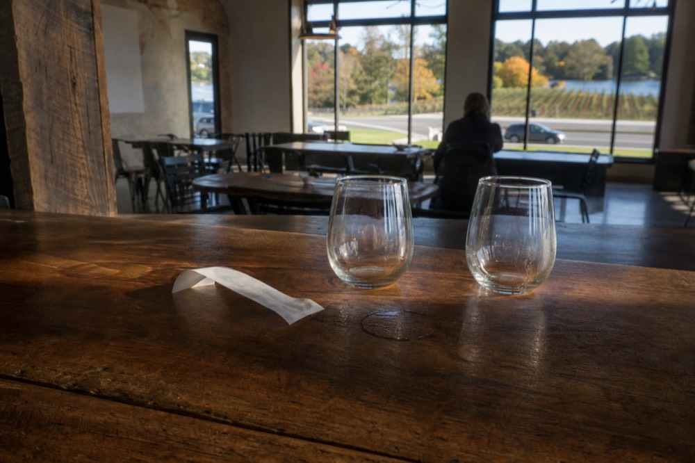 A receipt and a few wine glasses on a tasting bar counter