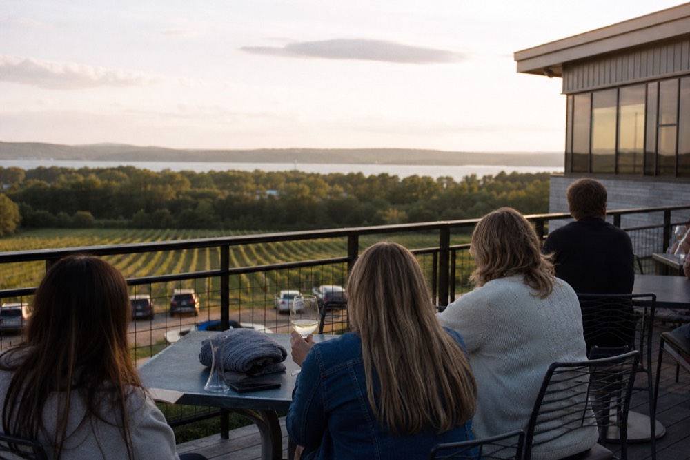 A small group sharing wine glasses at an outdoor vineyard table at their own pace