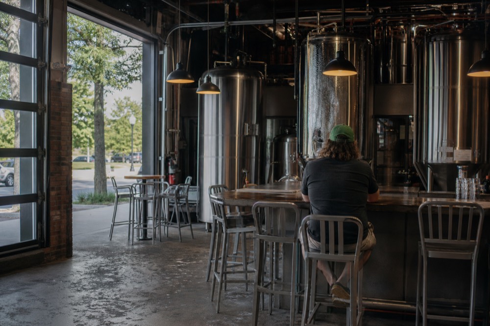 A brewery taproom interior with stainless tanks behind the bar