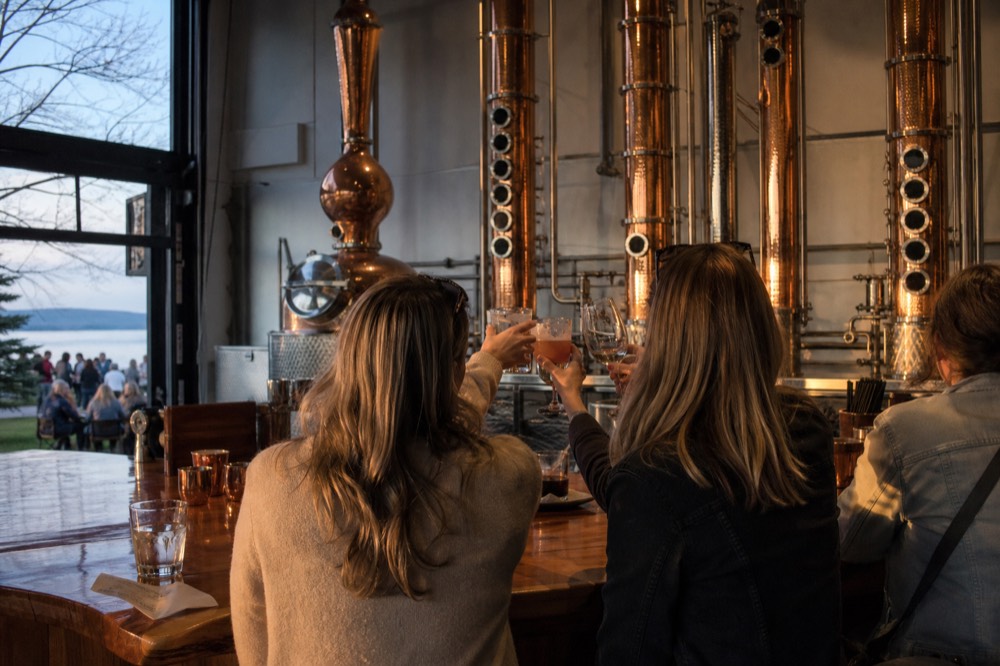 Friends toasting with mixed drinks and wine glasses at a distillery bar