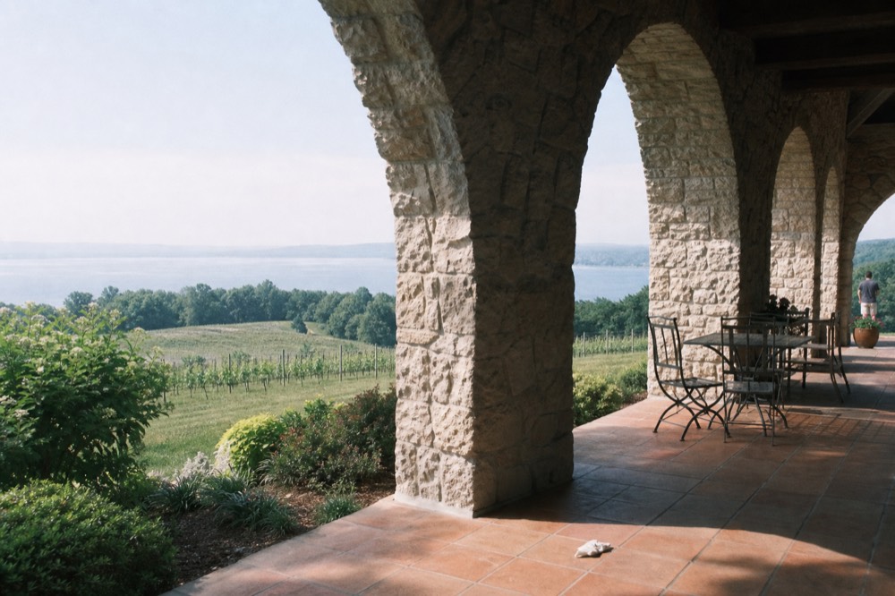 A tasting room terrace overlooking a calm bay with vineyard land beyond