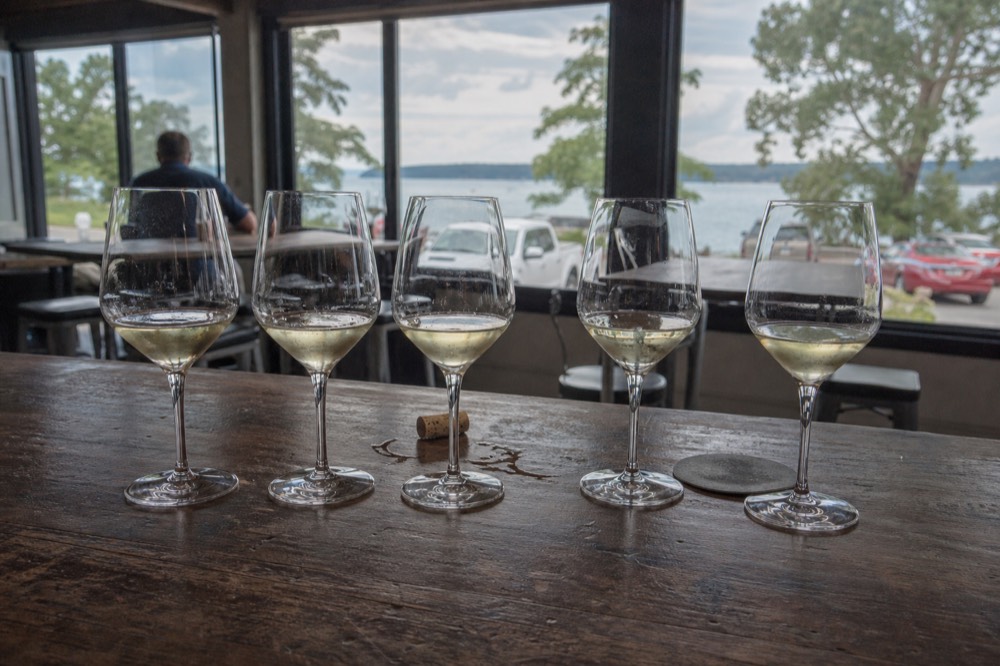 Tasting glasses lined on a wooden bar with bay light behind