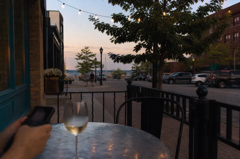 A phone held by a visitor browsing listings beside a glass of wine on an outdoor patio