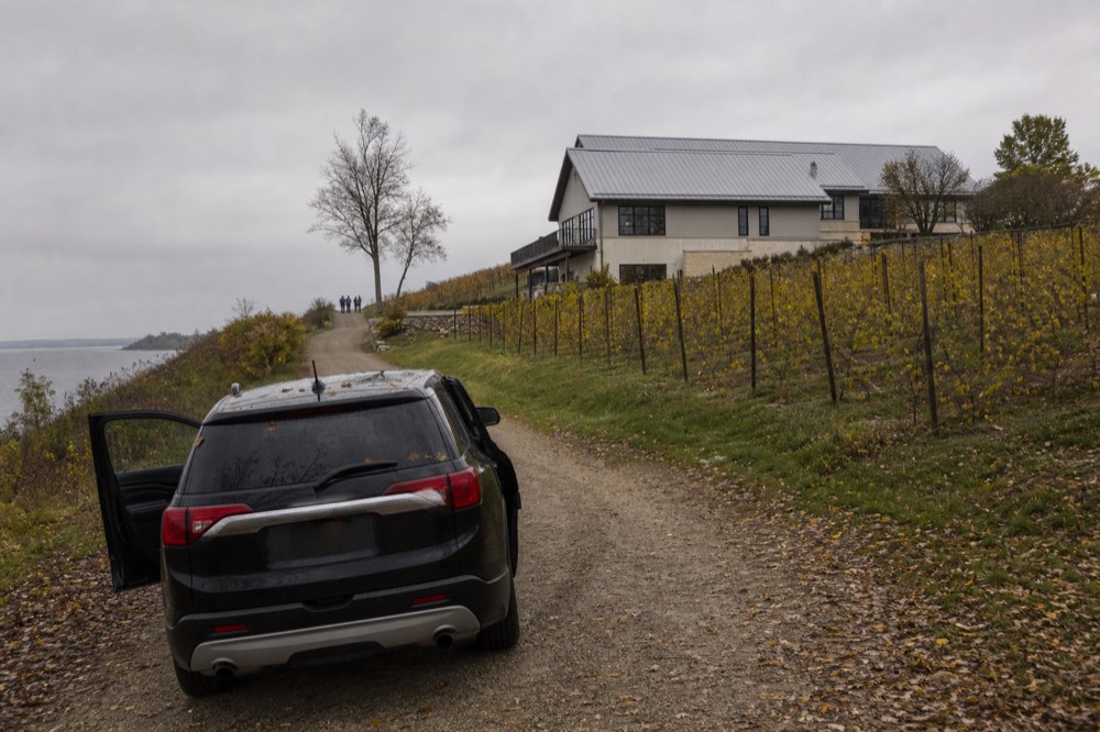 A black SUV parked on a gravel drive in front of a peninsula winery